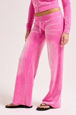 Displays a model wearing the Super Pink washed 'Juicy' branded OG straight track pant 