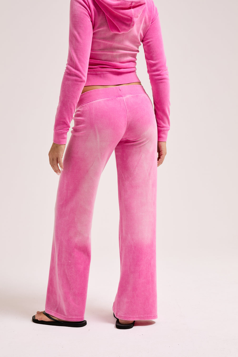 Displays a model wearing the Super Pink washed 'Juicy' branded OG straight track pant 