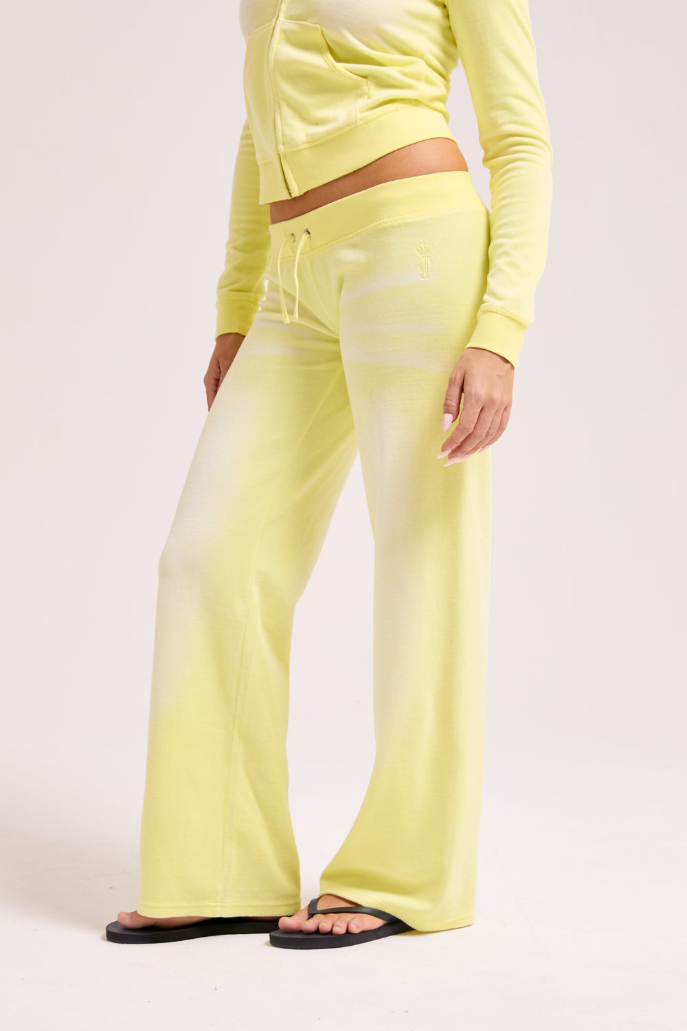 Displays a model wearing the Yellow pear washed 'Juicy' branded OG straight track pant 
