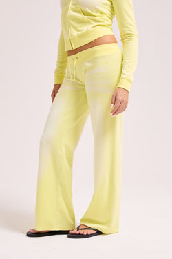 Displays a model wearing the Yellow pear washed 'Juicy' branded OG straight track pant 
