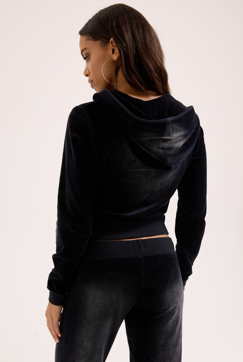 Displays a model wearing the washed black cotton 'Juicy' branded velour og straight low rise pants 