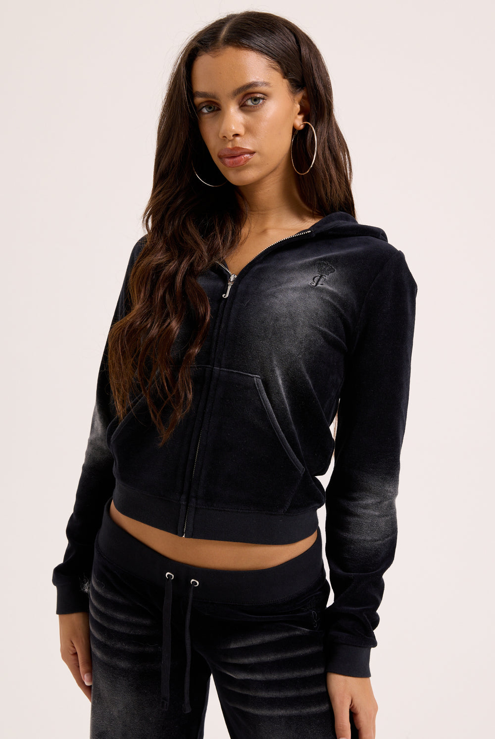 Displays a model wearing the washed black cotton 'Juicy' branded velour heritage hoodie 