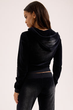 Displays a model wearing the washed black cotton 'Juicy' branded velour heritage hoodie 