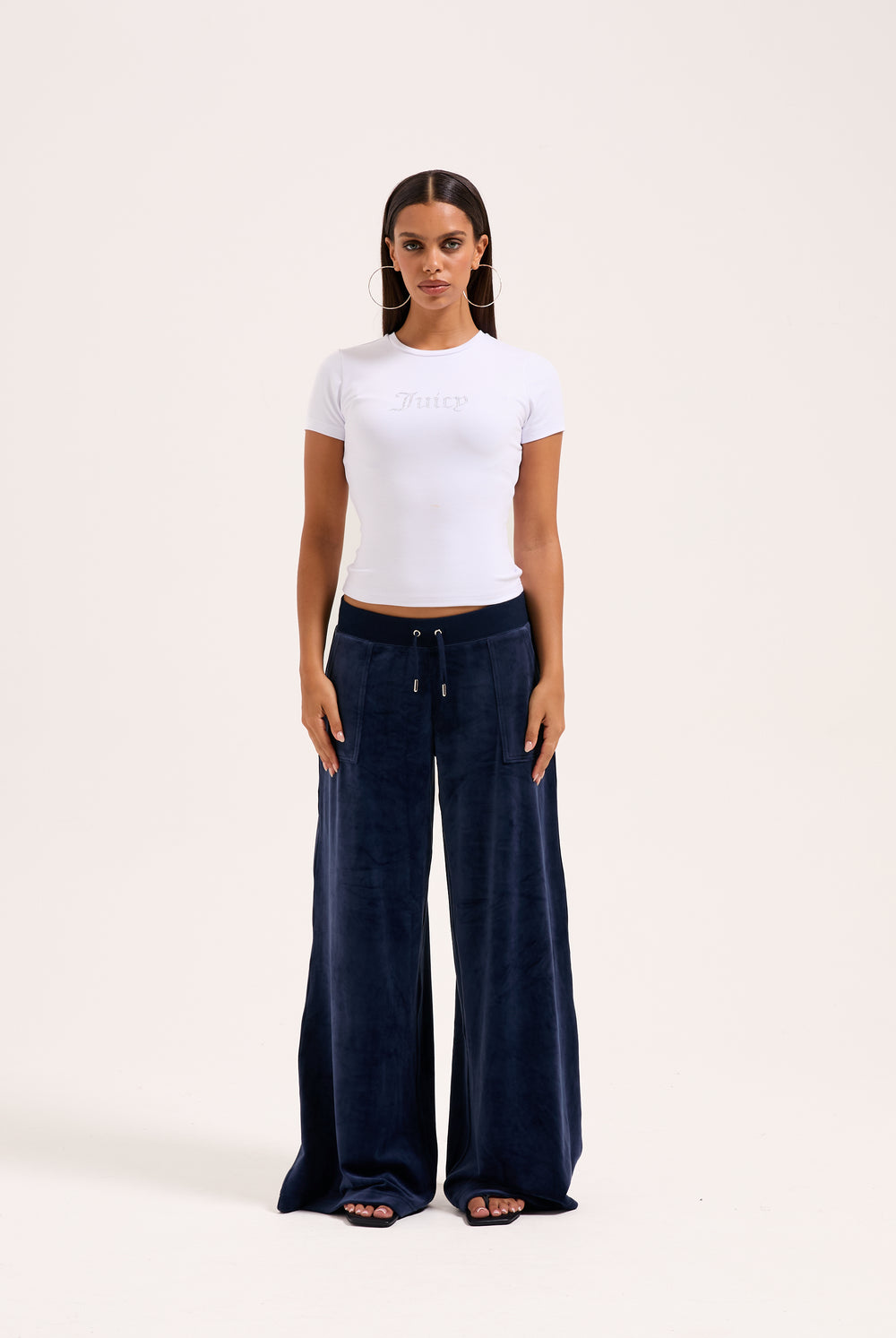 Displays a model wearing the night sky 'juicy' branded Sky Wide leg classic velour track pant 