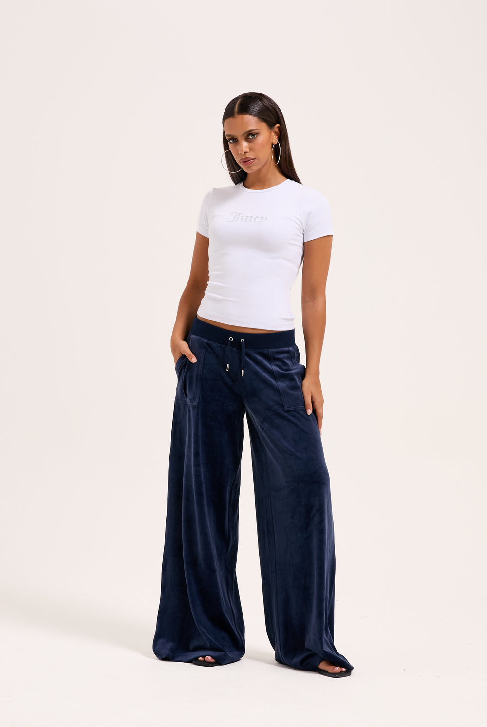 Displays a model wearing the night sky 'juicy' branded Sky Wide leg classic velour track pant 