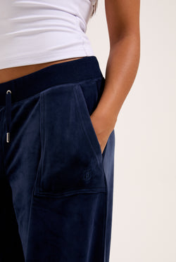 Displays a model wearing the night sky 'juicy' branded Sky Wide leg classic velour track pant 