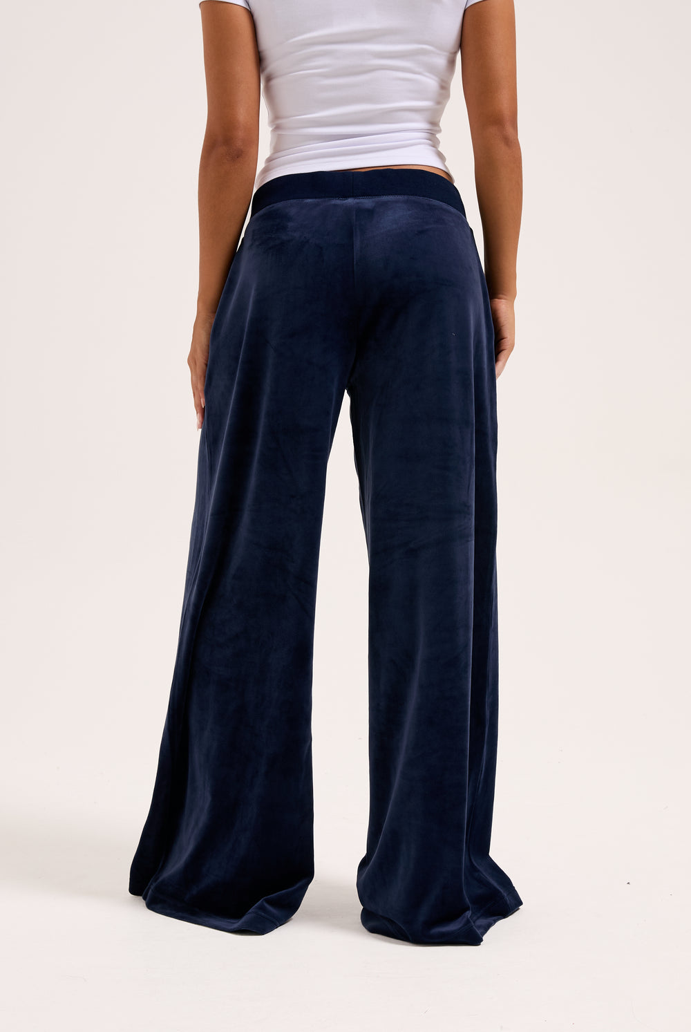 Displays a model wearing the night sky 'juicy' branded Sky Wide leg classic velour track pant 
