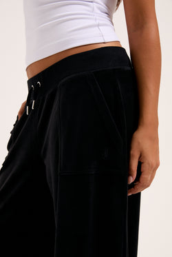 Display a model wearing the Black 'Juicy' branded wide leg classic velour track pant 